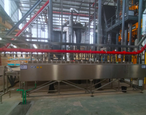 industrial stainless steel inline washer system installed in a manufacturing facility with piping and structural framework