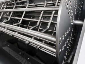 Angled view of the rotating basket inside a fixed basket blaster designed to securely hold parts while providing consistent abrasive blasting coverage.
