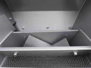 High-performance blast wheel mounted on a tumbler blaster used to propel abrasive media at high velocity for cleaning and surface preparation of industrial parts.