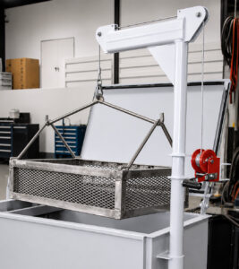 Optional overhead crane system positioned above a hot tank, designed to safely lift, transport, and lower heavy parts and baskets into the cleaning solution.