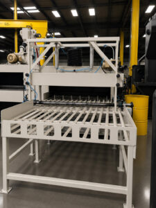 Exit ramp of a flow-through cylinder polisher used to smoothly discharge finished cylinders to the next stage of processing.