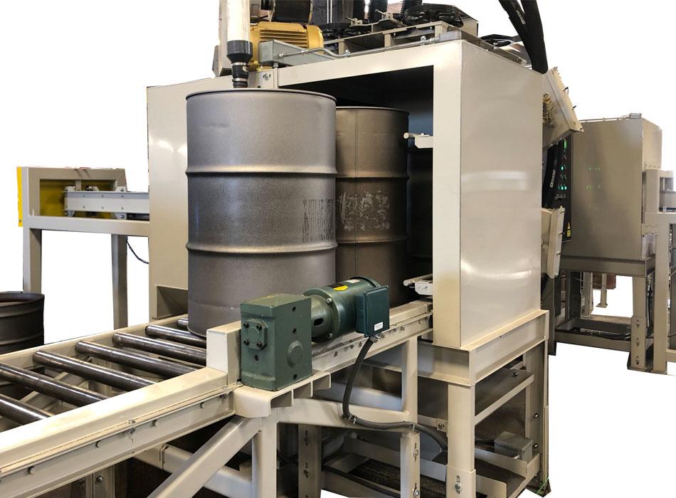 Entrance view of a flow-through blaster showing clean drums at the entry point of the system for continuous abrasive blasting of parts.