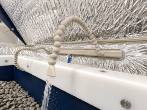 Spray hoses inside a vibratory tub finishing system providing controlled delivery of water, compounds, and process additives directly into the finishing chamber.