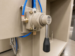 Hydraulic monorail switch mechanism at a powder coat booth used to automatically direct carriers between the coating booth and downstream production equipment.
