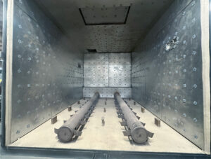 Pull-out racks inside a walk-in burn-off oven used for easy loading, unloading, and positioning of parts during thermal cleaning.