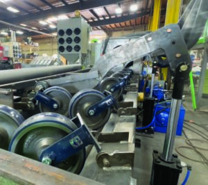 Pipe kicker mechanism used to transfer pipes from a pipe blaster to the next stage of an automated processing system.