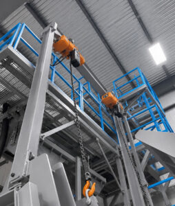 Door lifting system on a slat blaster designed to raise and lower the blast cabinet door for efficient loading and unloading of large industrial parts.