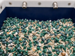 Interior view of a vibratory tub finishing system filled with mixed finishing media, showcasing the processing chamber where parts and media interact during the finishing cycle.