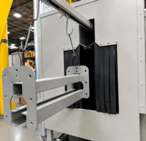 Monorail conveyor transporting parts through a monorail flow-through washer, carrying components through wash, rinse, and drying stages for automated cleaning.