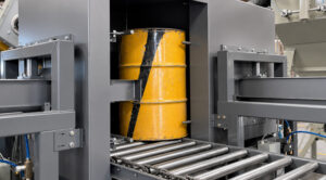 Drum pusher mechanism on a flow-through drum blaster used to automatically advance steel drums into the blasting chamber for processing.