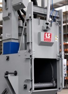 Optional roll-up door on a rubber belt blaster providing convenient access to the blasting chamber for loading and unloading parts.