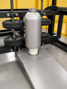 Cylinder polisher holding and rotating a freshly blasted gas cylinder between multiple drive wheels for consistent surface finishing and polishing.