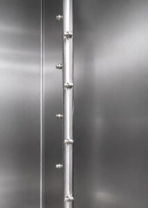Industrial spray nozzle inside a small table washer delivering high-pressure cleaning solution to remove contaminants from parts during the wash cycle.