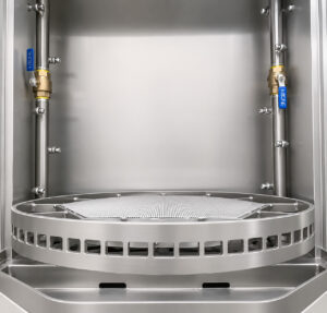 Rotating table inside a small table washer designed to support and rotate parts during the cleaning cycle for complete spray coverage and consistent cleaning results.