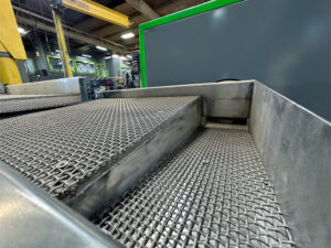 Vibratory separator ramp leading to a corn cob dryer used for separating media and drying parts after vibratory finishing.