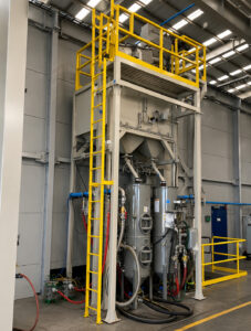 Angled view of a blast pot used in a blast room to store and deliver abrasive media for manual blasting operations.