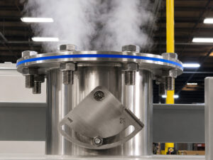Exhaust vent on a chain mesh belt flow-through washer releasing steam from the wash chamber during operation to remove heat, moisture, and vapors from the system.