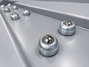 Heavy-duty roller balls on an upender/downender automation and handling system designed to support smooth rotation and controlled movement of parts during repositioning operations.