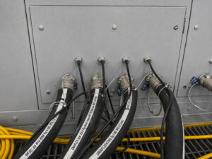 Four blast hose connections on a blast room pressure vessel used to supply abrasive media and air to multiple operators during blasting operations.