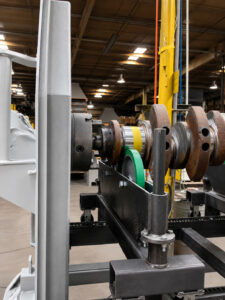 Close-up view of a crankshaft before entering a crankshaft blaster, highlighting the clamping system that securely holds the crankshaft during the blasting process.