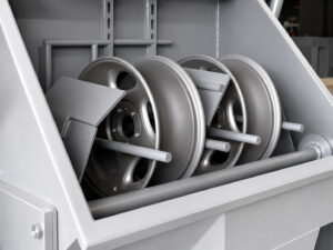 Inside view of a wheel rim blaster showing the blasting chamber and wheel positioning system used to clean and prepare rims for finishing operations.