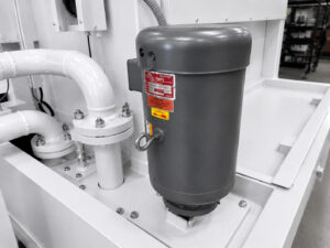 Industrial water pump on a batch door-mounted table washer circulating cleaning solution to the spray nozzles for consistent high-pressure cleaning performance.