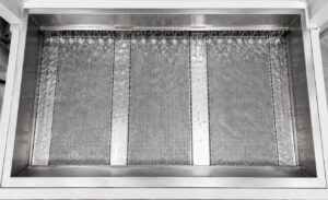 Oil skimmer on a batch door-mounted table washer continuously removing floating oils and contaminants from the wash solution to maintain cleaning performance and solution quality.