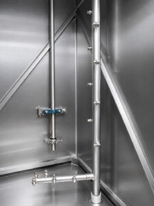 Close-up view of the spray nozzles inside a batch door-mounted table washer, delivering high-pressure cleaning solution to parts from multiple directions for complete cleaning coverage.