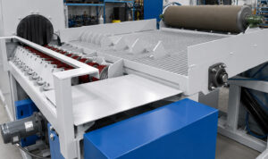 Side view of the entrance to a flow-through cylinder blaster showing the cylinder positioning stopper that prevents cylinders from entering the machine too early.