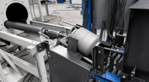 Close-up view of a freshly blasted 20 lb propane tank transferring from the exit of a flow-through cylinder blaster onto an automated handling system for the next process.
