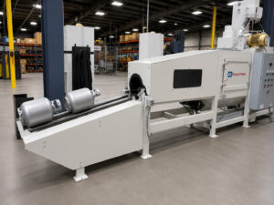 Wide view of the exit section of a flow-through cylinder blaster showing a freshly blasted 20 lb propane tank positioned on the discharge conveyor.