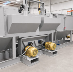 Impeller motors mounted on the rear of a flow-through cylinder blaster that power the blast wheels used for abrasive cleaning of cylinders.