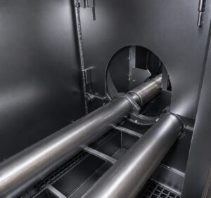 Interior view of the blast zone rollers inside a flow-through cylinder blaster used to support and rotate cylinders during the blasting process.