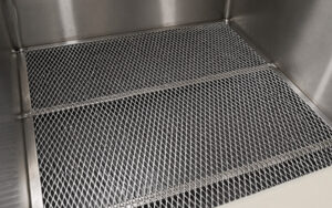 Interior view of a dip tank showing a component immersed in cleaning solution, highlighting the tank's open design and chemical cleaning process used for industrial parts.