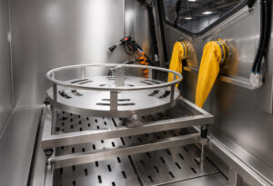 Interior view of a pressure washer cabinet showing the wash chamber, spray nozzles, work area, and cleaning system designed for high-pressure industrial part cleaning.