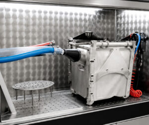 Inside view of the LS Industries Diesel Particulate Filter Washer (DPFX) showing the stainless-steel wash chamber, filter holding fixture, and high-pressure spray system designed to clean diesel particulate filters from multiple angles.