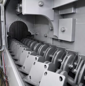 Interior view of the blast zone inside a flow-through cylinder blaster showing cylinders being cleaned by high-velocity abrasive media.