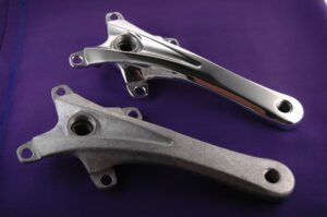 Aluminum part before and after surface finishing showing raw casting versus polished machined component for industrial cleaning and coating processes