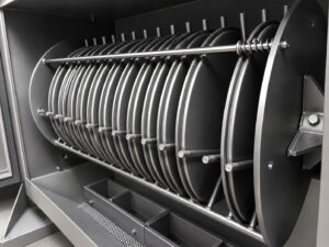 Rotating parts basket inside a batch drum lid blaster containing freshly blasted components with clean, uniform surfaces ready for the next manufacturing process.