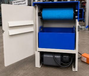 Debris collection system on a platen surface grinder capturing metal particles, grinding dust, abrasive residue, and coolant-contaminated debris generated during grinding operations.