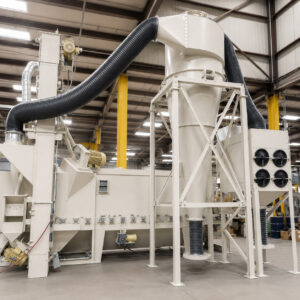 Shot blaster in the background with a cyclone separator connected to a dust collector in the foreground, forming a complete dust collection and air filtration system.