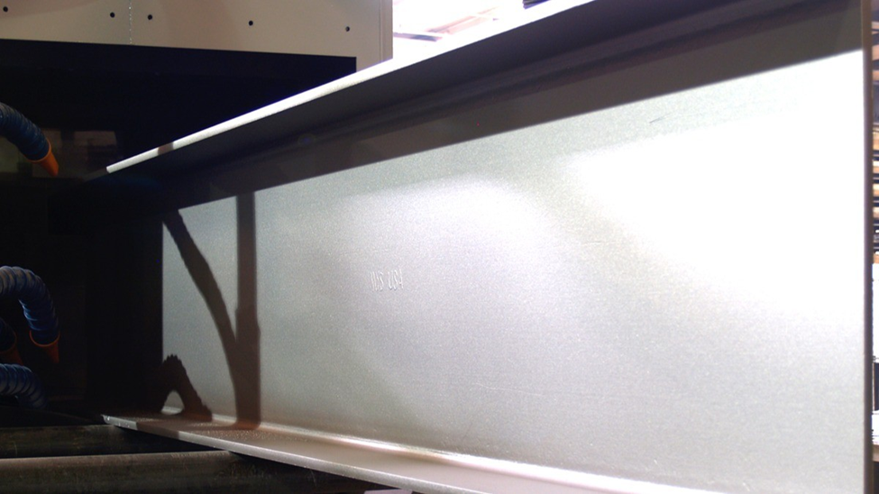 Shot blasted structural steel beam with uniform surface profile inside industrial blast cabinet preparing for coating adhesion