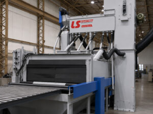 Entrance side of a plate blaster showing the loading area where steel plate enters the machine for automated surface preparation.