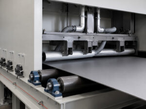 Optional air knife system on a plate blaster directing high-velocity air across a steel plate to remove excess abrasive media for recovery and reuse.