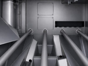 Interior view of a plate blaster showing the blast chamber, conveyor system, blast wheels, and abrasive blasting zone where steel plate is cleaned and surface prepared.