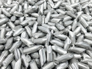 Large pile of cylindrical aluminum vibratory media used for deburring, polishing, burnishing, and surface finishing applications.