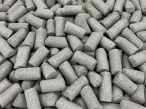 Large pile of cylindrical ceramic vibratory media used for aggressive deburring, edge radiusing, cleaning, and surface finishing of metal components.