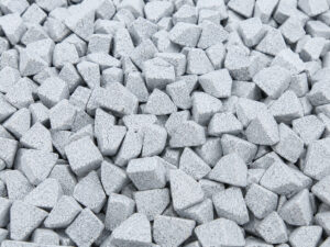 Large pile of triangular ceramic vibratory media used for aggressive deburring, edge radiusing, cleaning, and surface finishing of metal components.
