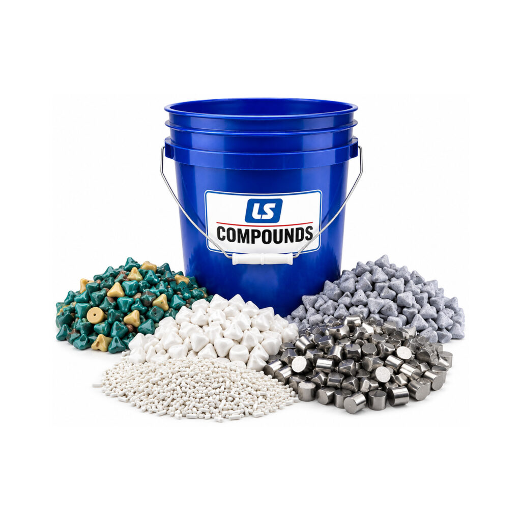 Blue 5-gallon bucket labeled "Compounds" surrounded by assorted vibratory finishing media, including plastic, ceramic, porcelain, and aluminum media scattered around the base.