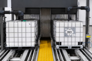 Dual-lane internal washing system inside an LS Industries Tote Washer, simultaneously cleaning the interiors of two IBC totes with high-pressure spray nozzles for maximum productivity.